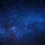 Purple and blue nebulae clouds scattered with countless bright stars and distant galaxies in the expanse of space.