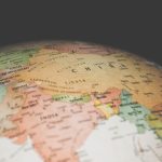 An antique-style desk globe with a sepia-toned world map resting on a wooden surface.