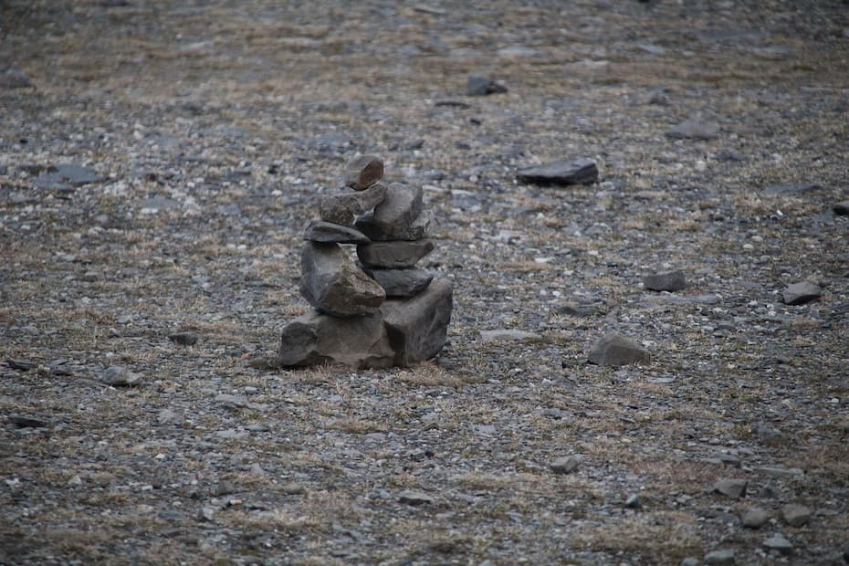 A moss-covered boulder in a forest that naturally resembles a grumpy troll face with two deep eye sockets and a protruding nose.