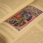 A close-up side-angle view of an open book focusing on a few lines of crisp text while the surrounding pages blur.