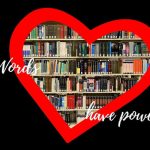 Open book with pages folded into a heart shape in front of a bookshelf.