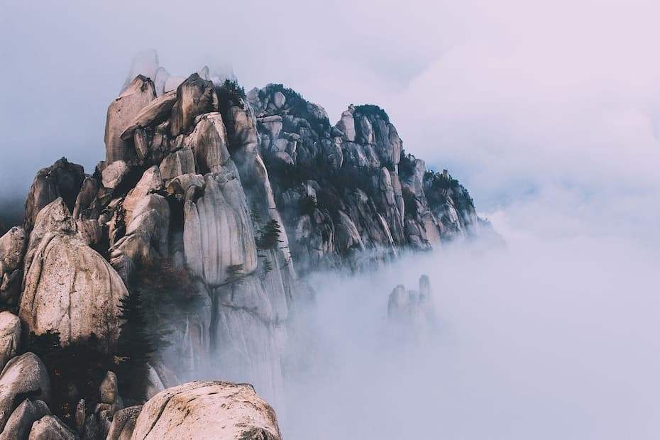 Jagged mountain peaks piercing through a thick layer of white mist and clouds