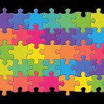 Colorful jigsaw puzzle made of interlocking pieces in shades of purple, blue, green, and yellow on a black background.