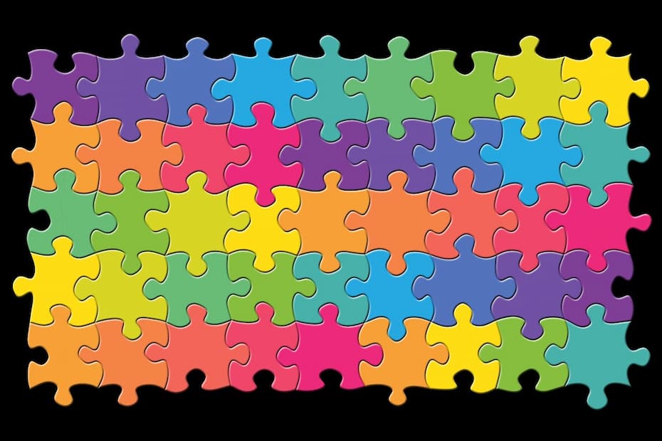 Colorful jigsaw puzzle made of interlocking pieces in shades of purple, blue, green, and yellow on a black background.