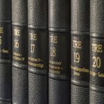 Volumes 14-21 of an encyclopedia on a shelf with matching black leather spines and gold lettering.