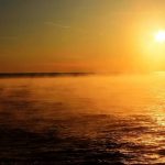 Misty sunrise over a dark-blue lake.