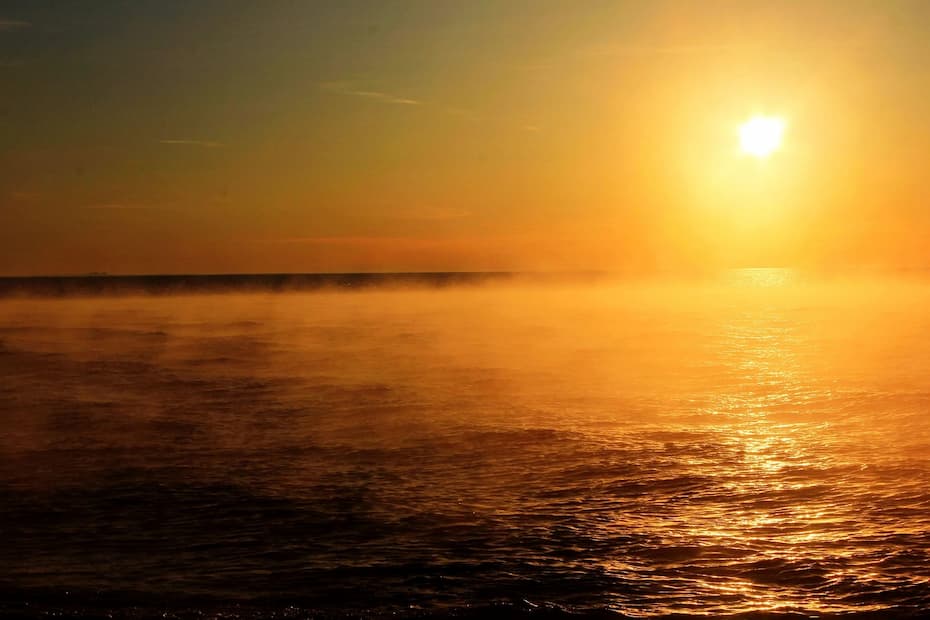 Misty sunrise over a dark-blue lake.