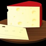 A wedge and slices of Swiss cheese full of holes on a wooden board.